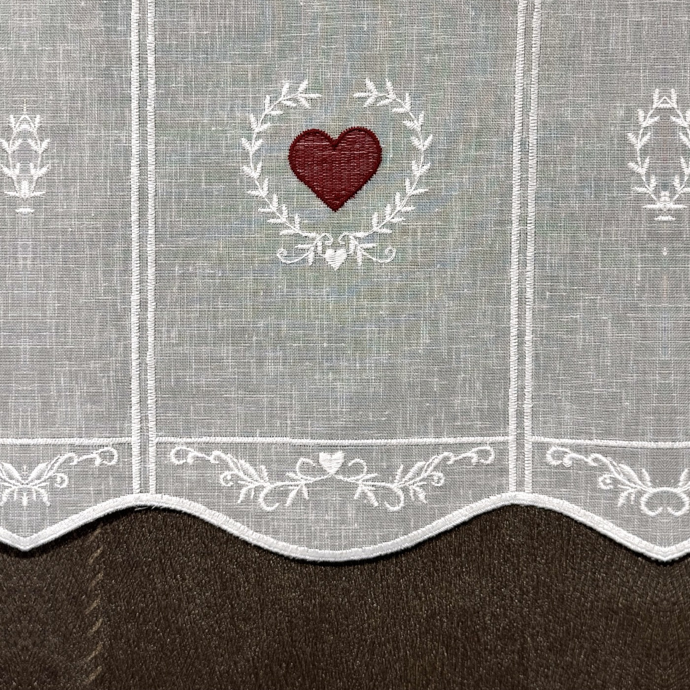 Détail de la broderie du brise-bise cœur en couronne rouge