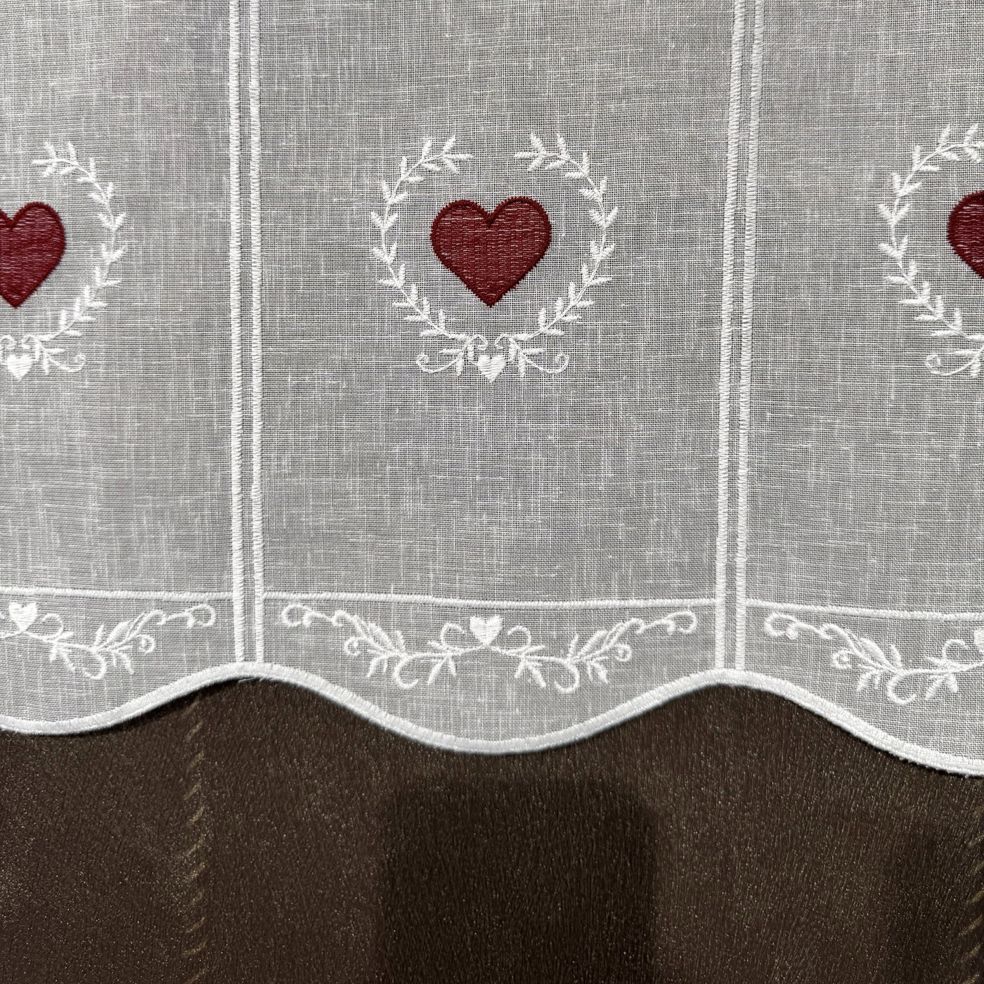 Détail de la broderie du brise-bise cœur en couronne rouge