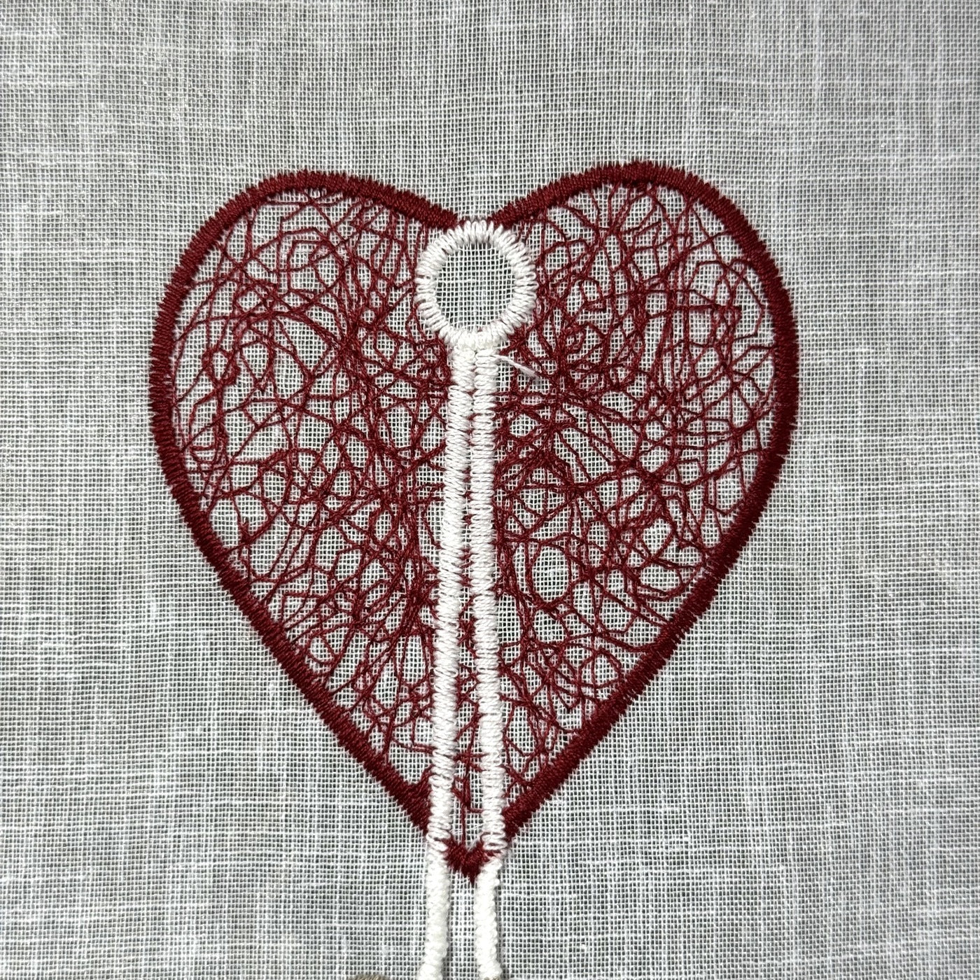 Détail de la broderie du brise-bise cœur filigrane et pampilles