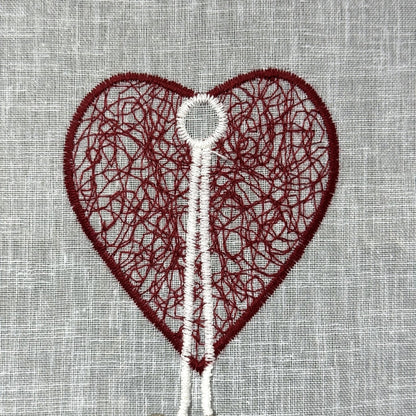 Détail de la broderie du brise-bise cœur filigrane et pampilles