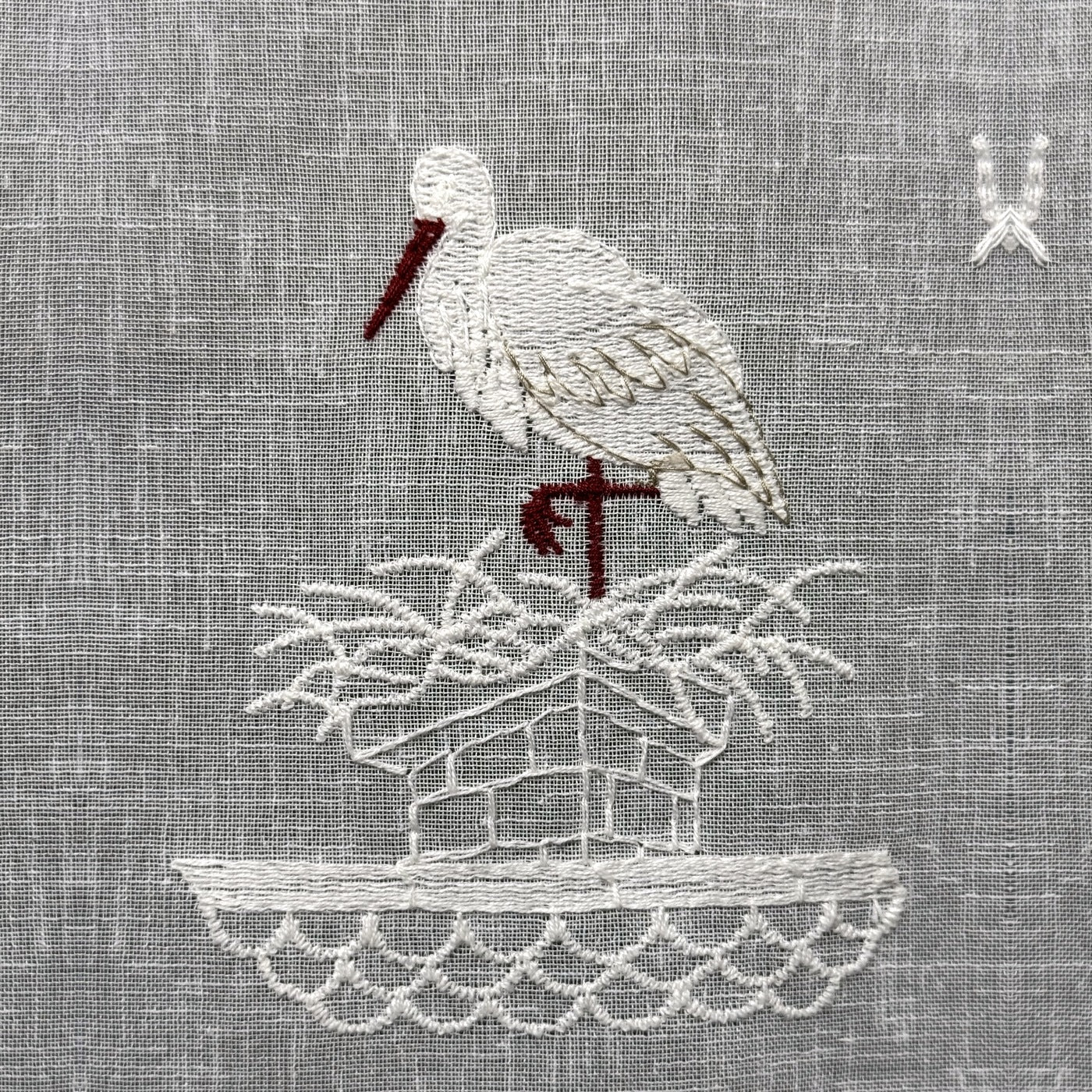 Gros plan du motif brodé du brise-bise cigogne