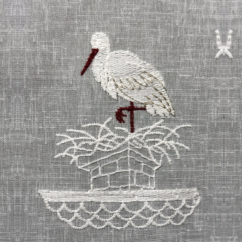 Gros plan du motif brodé du brise-bise cigogne
