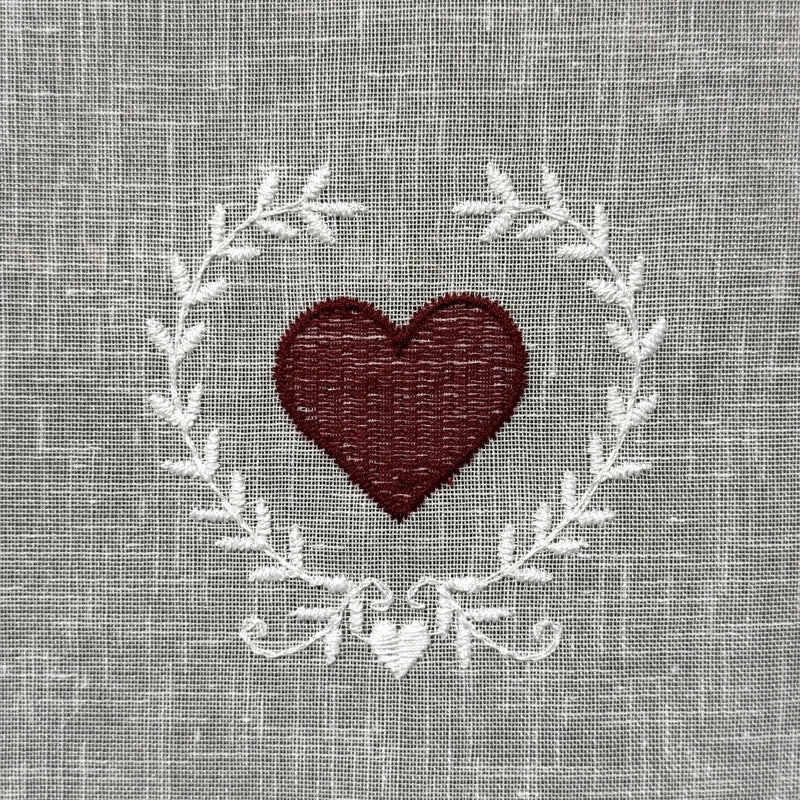 Gros plan du motif brodé du brise-bise cœur en couronne rouge