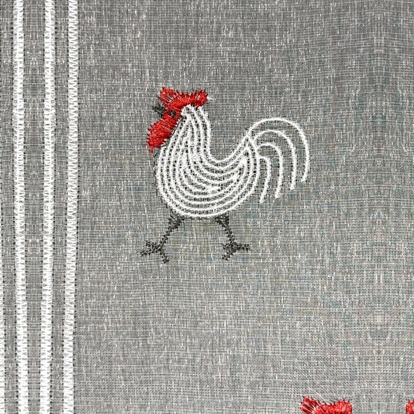 Gros plan du motif brodé du brise-bise coq
